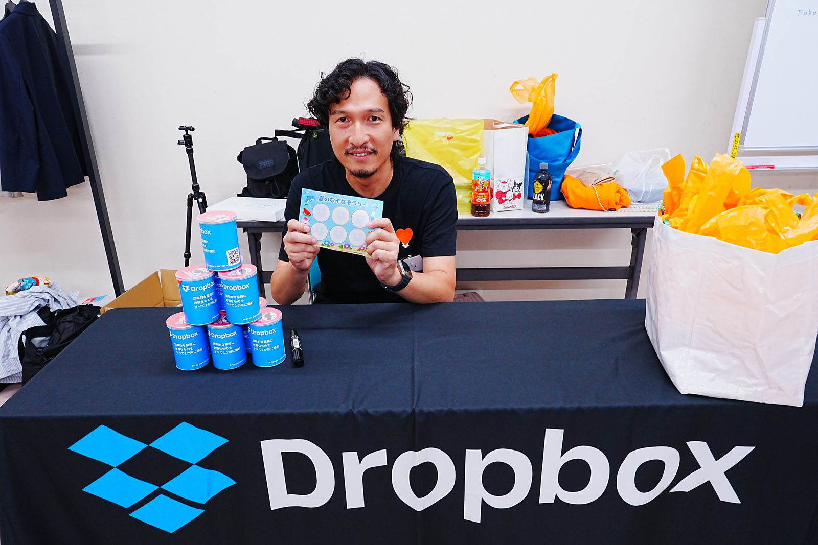Dropbox for Goodのブースでスタンプラリーの用紙を紹介するボランティアメンバー